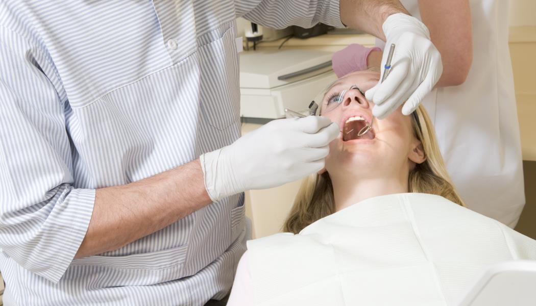 Dentist and assistant in exam room with woman in chair