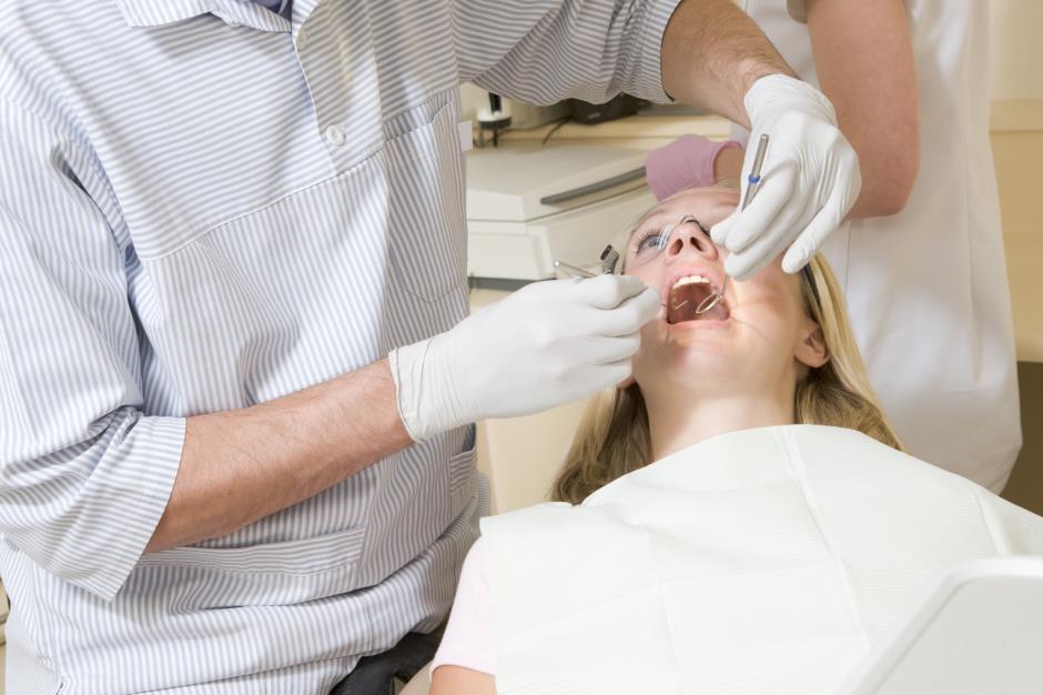 Dentist and assistant in exam room with woman in chair 